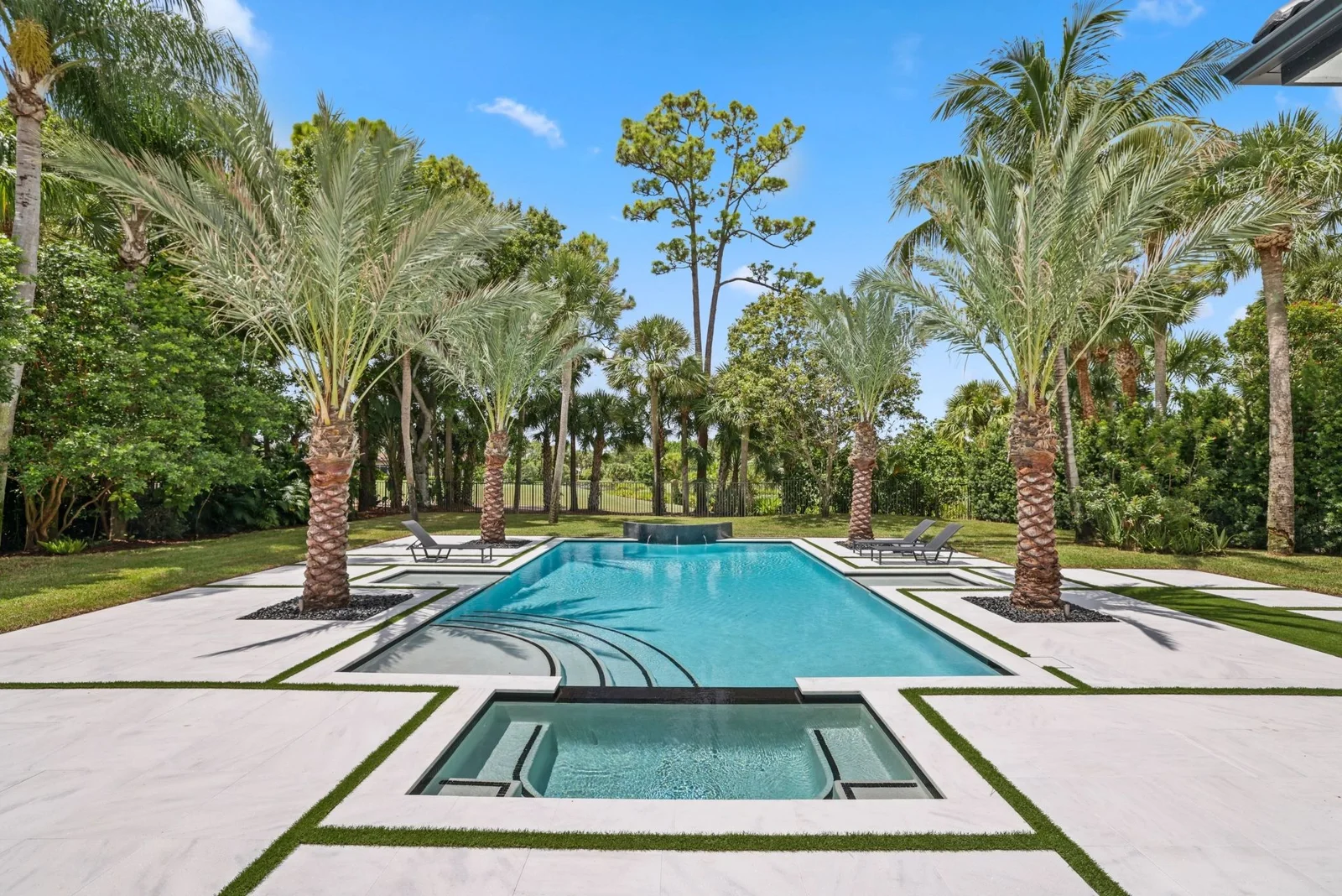 Medjool date palms with diamond-cut trunks outside a coastal home.